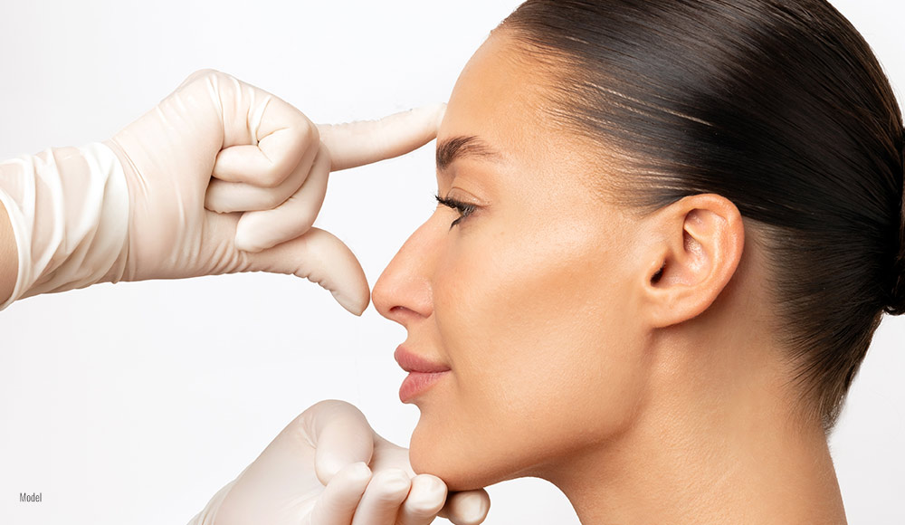 side profile of a woman's face while someone with gloved hands measures her facial features.